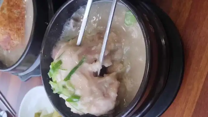 삼계탕 속 닭고기와 찹쌀밥을 젓가락으로 집는 모습