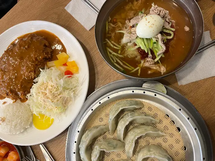 테이블에 차려진 밀면, 돈까스, 만두