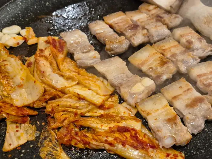 불판 위에서 익어가는 삼겹살과 김치