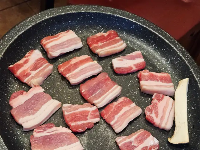불판 위에 올려진 두툼한 삼겹살 조각들