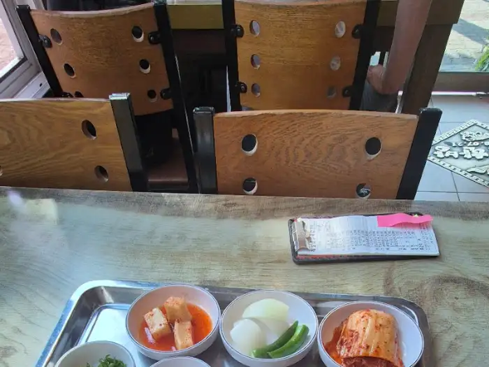 테이블 위에 차려진 기본 찬과 나무 의자 이미지