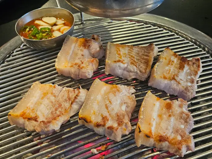 불판 위에서 익고 있는 두툼한 고기 덩어리