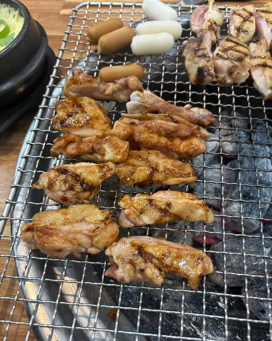 숯불 위에서 익어가는 닭갈비와 곁들임 메뉴