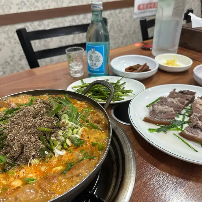 삼부회관 내부 풍경, 테이블 위에는 식사 메뉴와 함께 술병, 소주잔, 밑반찬들이 정갈하게 차려져 있습니다.