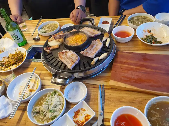 불판 위에서 익어가는 고기와 곁들임 메뉴