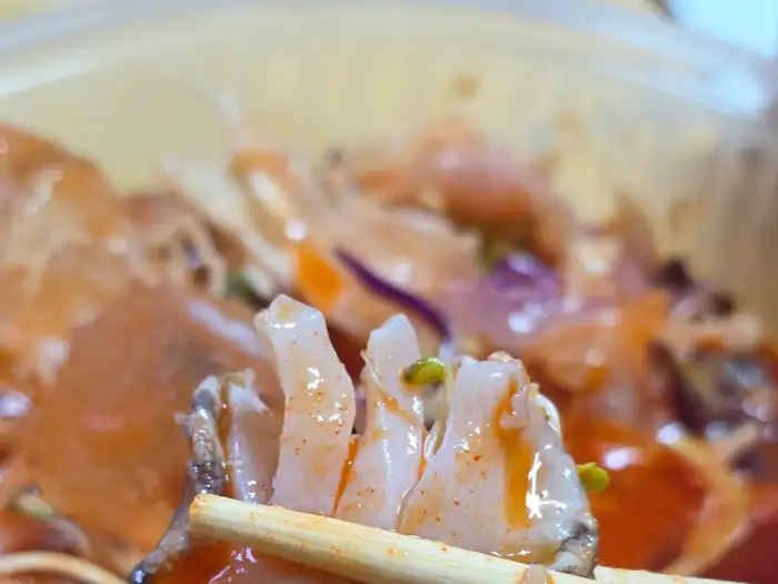 물회 육수에 말린 메밀 막국수 면을 젓가락으로 집어 올린 모습.