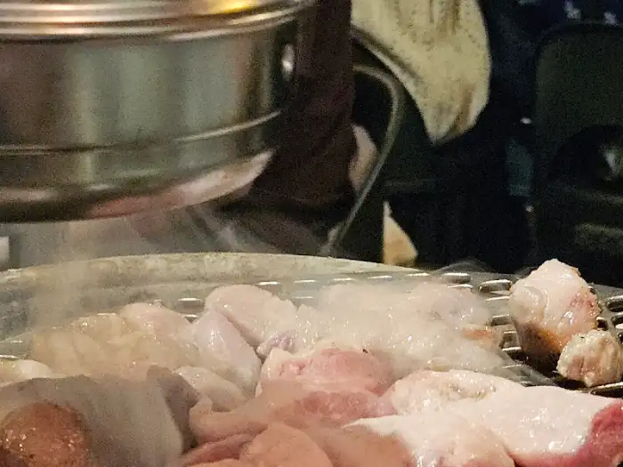 불판 위에 가지런히 놓인 여러 부위의 돼지고기